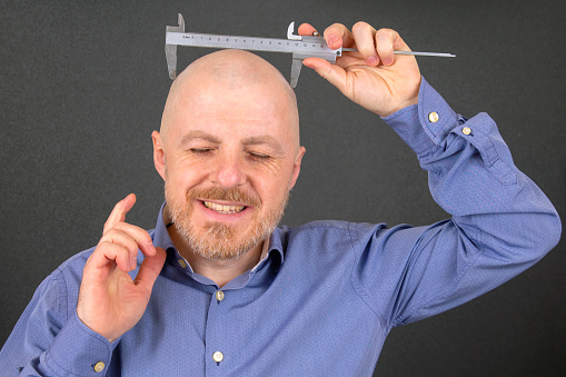man-measures-the-size-of-his-head-measuring-device-caliper-picture-id1144872540